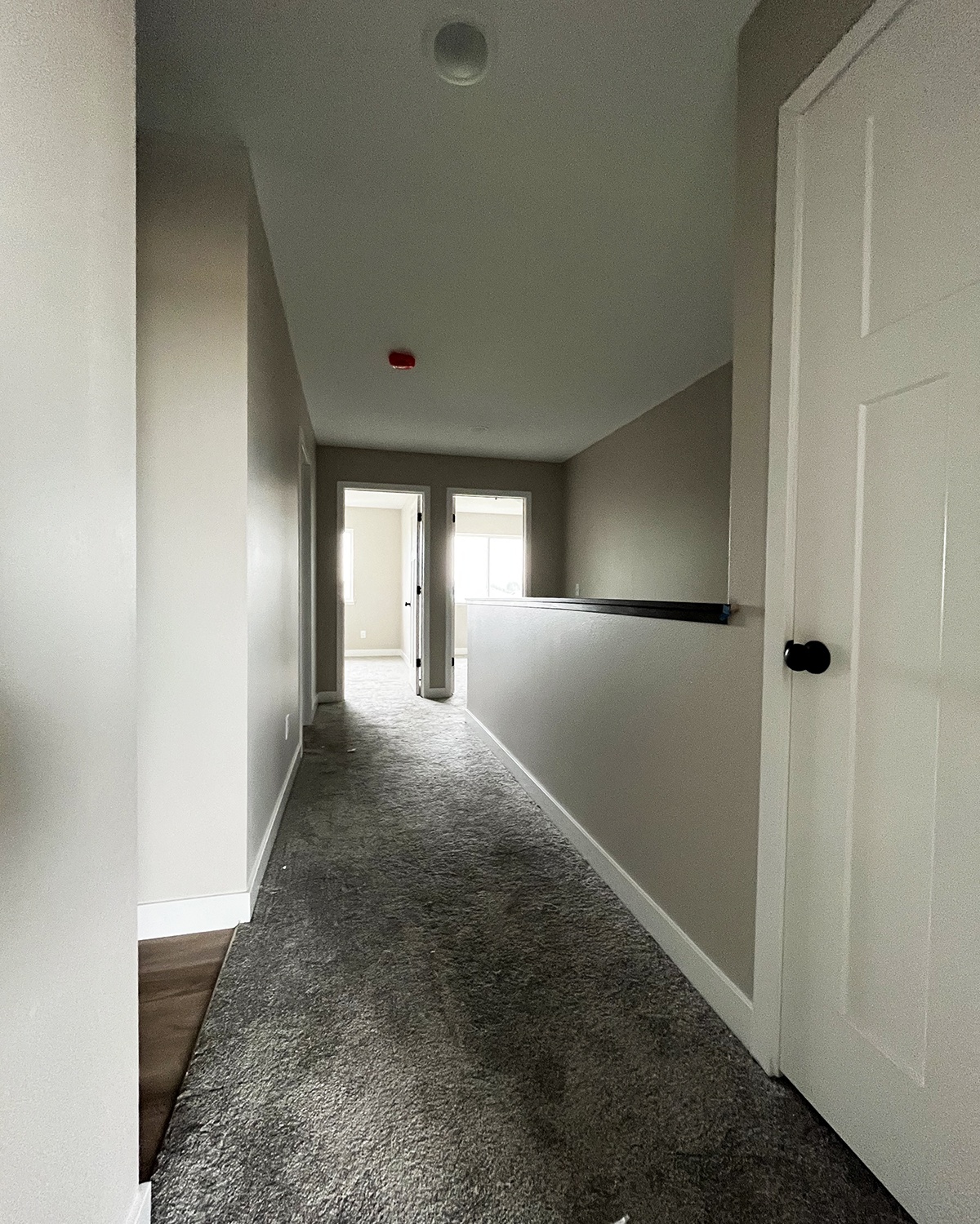 a long hallway with a white door and gray carpet